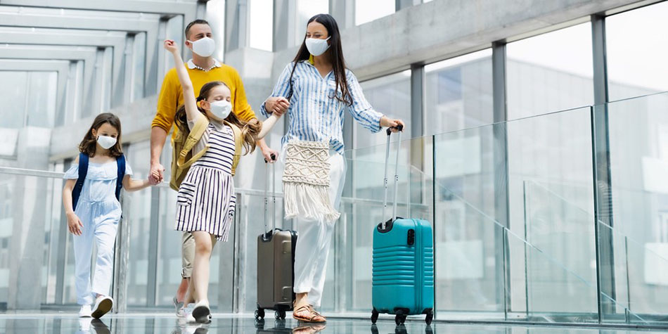 A vacationing family of four walks through a breezeway at the airport.