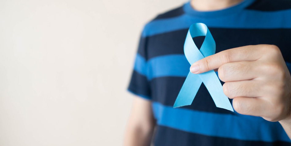 A man in striped shirt holds a blue ribbon.