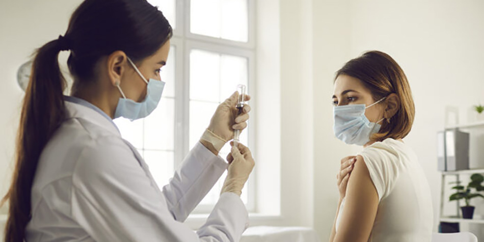 A medical professional prepares to give an older woman a flu shot.